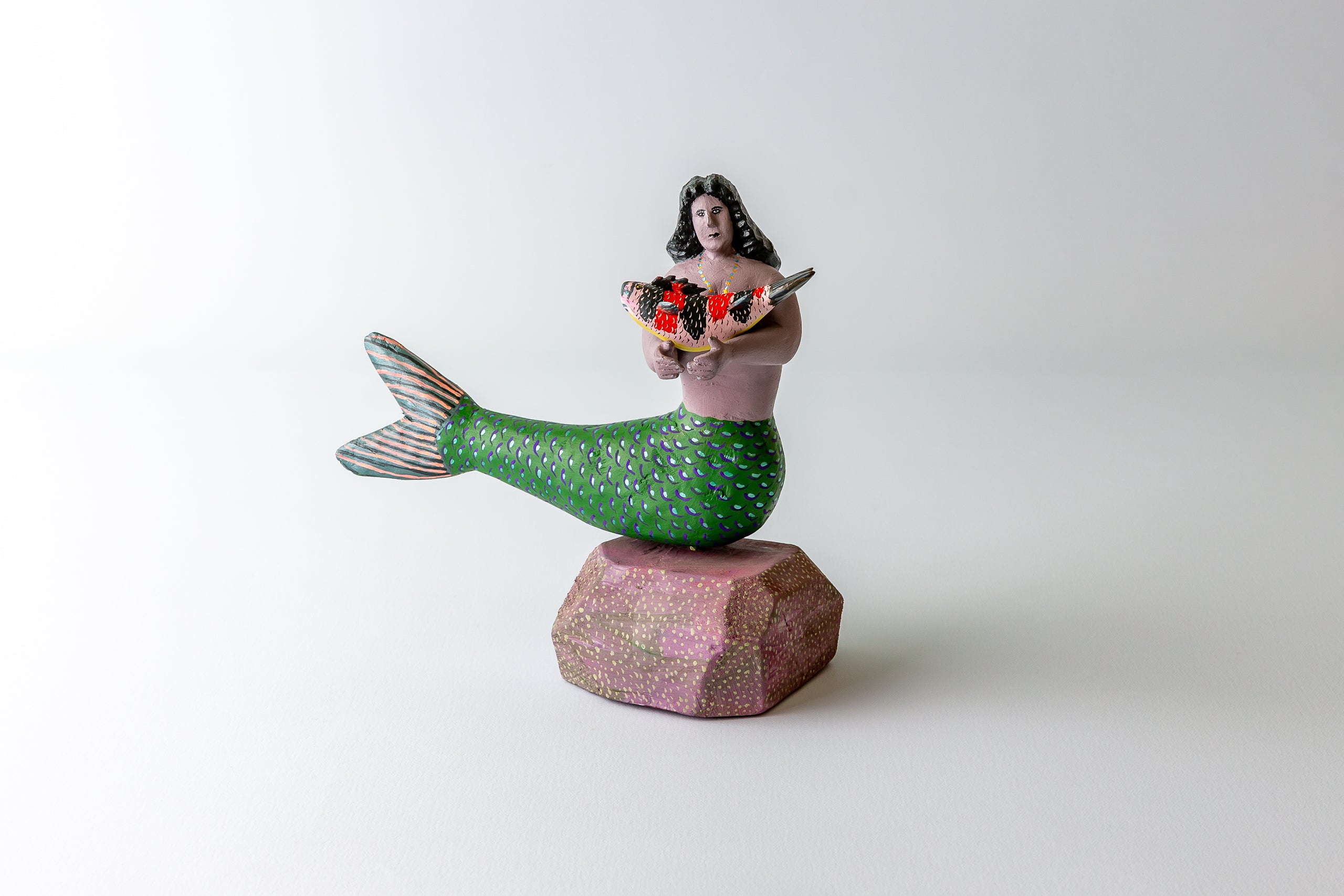 A beautiful mermaid with fine features carying a large fish.